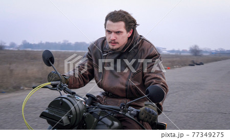 A furious anger motorbike rider fast moving country road on sunny windy day. 77349275