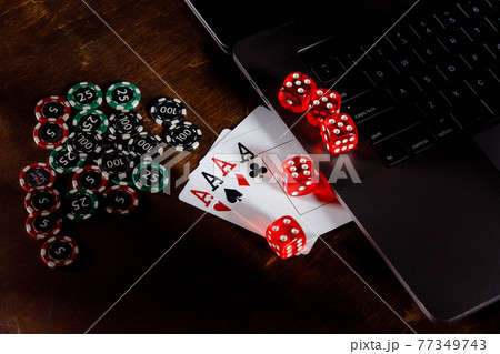 Online gambling and casino concept. Red playing dice, chips and cards on a wooden desk Online gambling and casino concept. Red playing dice, chips and cards on a wooden desk 77349743