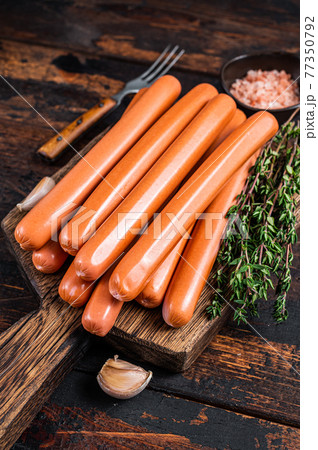 Frankfurter sausages on wooden cutting board. Dark Wooden background. Top view Frankfurter sausages on wooden cutting board. Dark Wooden background. Top view 77350792