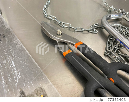 Large iron sharp metal scissors metal cutters lie on an iron table. Hand-held locksmith tools. The background 77351408