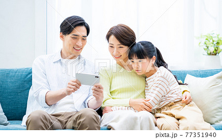 スマホで動画を見る若い家族 スマホで動画を見る若い家族 77351940