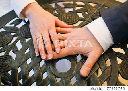 Bride and groom hands on table, romantic closeup 77352776