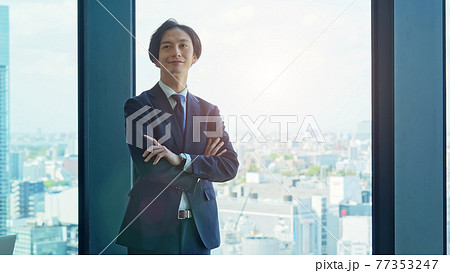 窓から街を眺めるビジネスマン 77353247