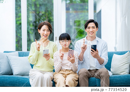 リビングでスマホを持つミドルの家族 リビングでスマホを持つミドルの家族 77354520