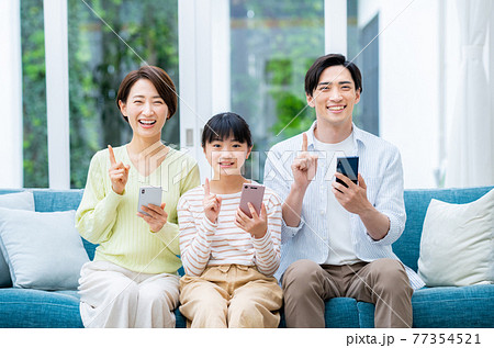 リビングでスマホを持つミドルの家族 リビングでスマホを持つミドルの家族 77354521