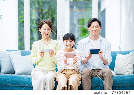 リビングでスマホを持つミドルの家族 リビングでスマホを持つミドルの家族 77354564