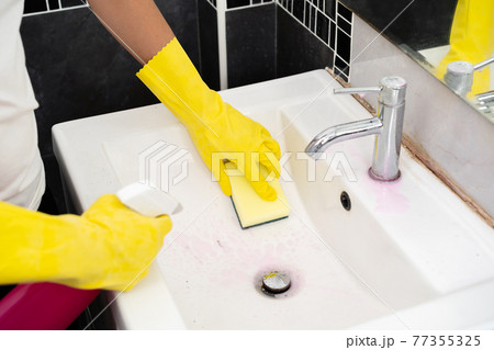 hand cleaning bathroom sink with spray and sponge 77355325
