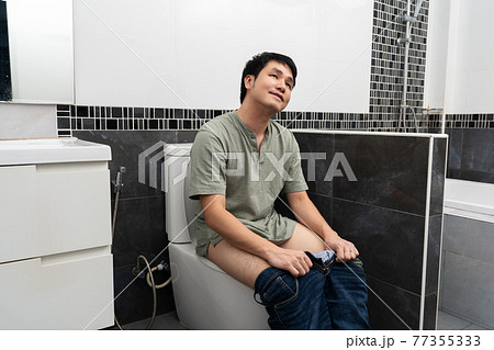happy man sitting in toilet bowl in bathroom at home 77355333