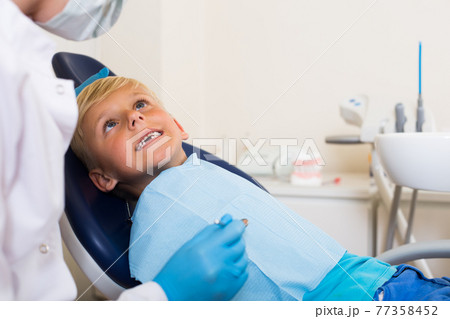 Dentist in uniform is taking examination of a teenager 77358452