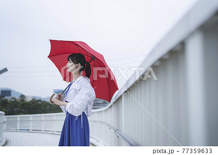 雨の日に傘をさす女性 77359633