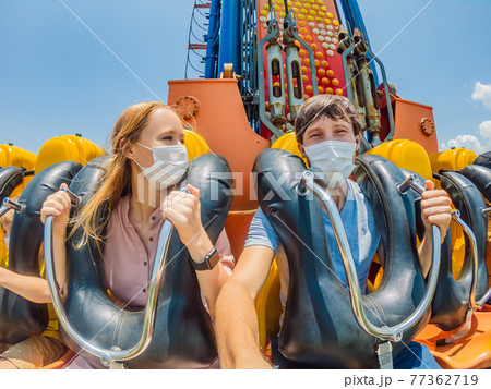 Family wearing a medical mask during COVID-19 coronavirus at an amusement park Family wearing a medical mask during COVID-19 coronavirus at an amusement park 77362719