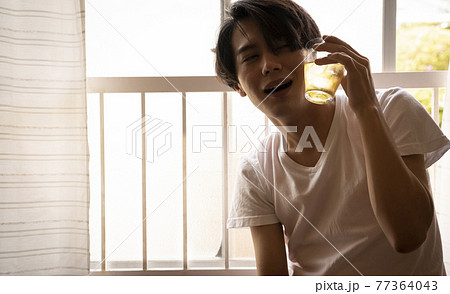 暑い日に部屋でお茶を飲む男性 77364043