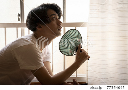 暑い日に部屋でスマホを見る男性 77364045