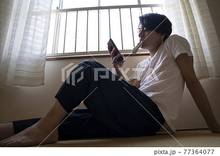 部屋でアイスを食べる男性 77364077