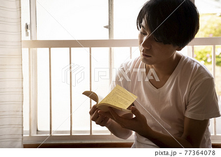 部屋で読書する男性 77364078