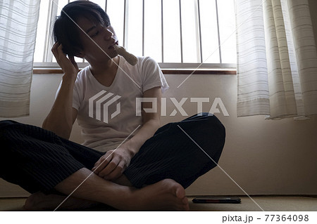部屋でアイスを食べる男性 77364098