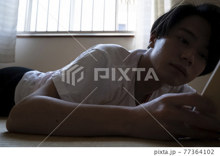 部屋で読書する男性 77364102