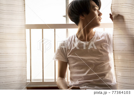 暑い日に部屋でくつろぐ男性 77364103