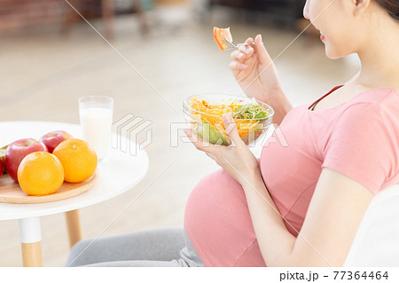 Asian pregnant woman eating salad 77364464