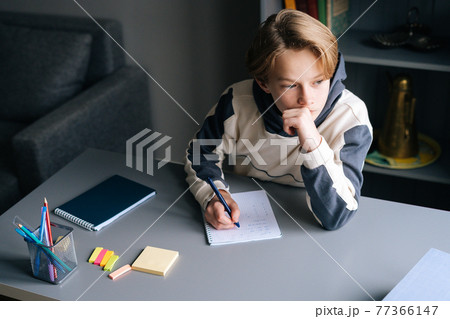 Close-up hands of pupil boy writing in notebook solving math equations sitting at desk at home. 77366147