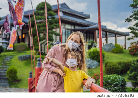 Mother and son travelers in medical mask looking at the Japanese traditional building. Tourists travel in Japan after the coronavirus epidemic Mother and son travelers in medical mask looking at the Japanese traditional building. Tourists travel in Japan after the coronavirus epidemic 77366292