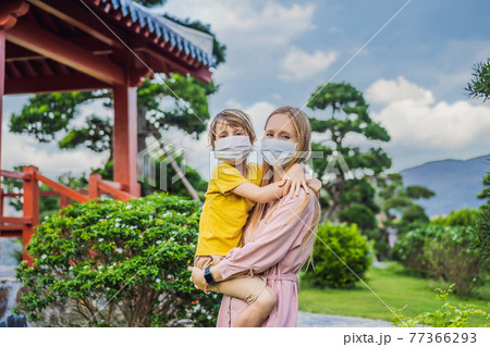 Mother and son travelers in medical mask looking at the Japanese traditional building. Tourists travel in Japan after the coronavirus epidemic 77366293