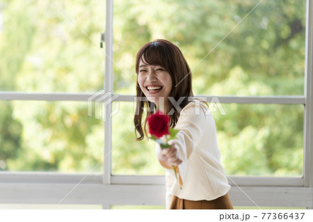 1輪の薔薇を窓辺で前に差し出す若い女性 1輪の薔薇を窓辺で前に差し出す若い女性 77366437