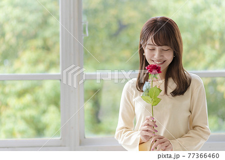 笑顔で薔薇の匂いを嗅ぐ若い女性 笑顔で薔薇の匂いを嗅ぐ若い女性 77366460