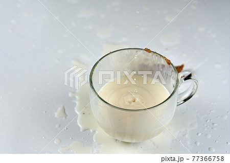 Splash of milk in a transparent glass mug 77366758