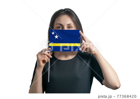 Happy young white woman holding flag Curacao flag and covers her face with it isolated on a white background 77368420