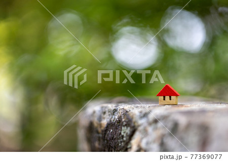 新緑背景の赤い屋根の小さな可愛い木製のおうち 77369077