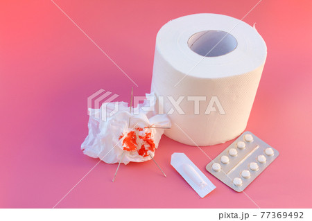 Toilet paper with blood, pills, candle. Concept of hemorrhoid treatment. 77369492