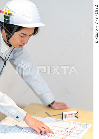 工事工程表を確認する現場監督 77371832