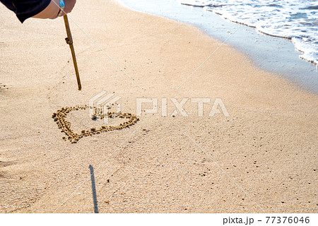 綺麗な海の波打ち際にハートを描く女性 浜辺 背景素材 の写真素材