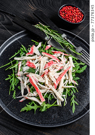 Crab meat on a plate with arugula. Black background. Top view 77376345