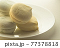 Delicious colored marshmallows on a round white plate is illuminated by the rear window 77378818