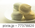 Delicious colored marshmallows on a round white plate is illuminated by the rear window 77378820