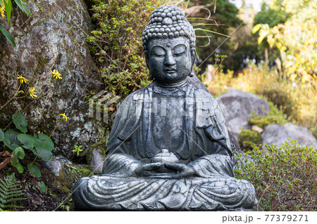 A stone figure of a Buddha sitting with a bowl and meditating A stone figure of a Buddha sitting with a bowl and meditating 77379271
