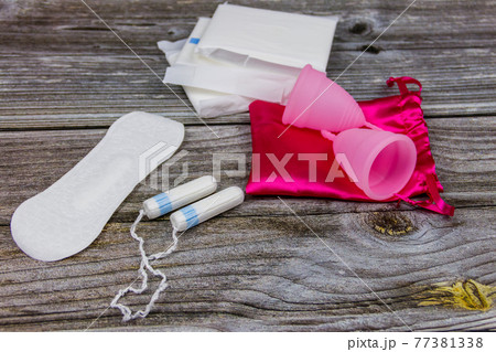 Sanitary pad, tampons and menstrual cup on wooden background. Concept of critical days, menstruation, feminine hygiene Sanitary pad, tampons and menstrual cup on wooden background. Concept of critical days, menstruation, feminine hygiene 77381338
