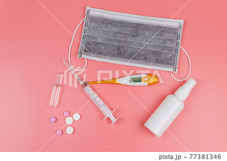 Concept of a prevention and treatment coronavirus. Medical mask, hand sanitizer, electronic thermometer, pills, syringe, ampoules on a pink background. Top view Concept of a prevention and treatment coronavirus. Medical mask, hand sanitizer, electronic thermometer, pills, syringe, ampoules on a pink background. Top view 77381346
