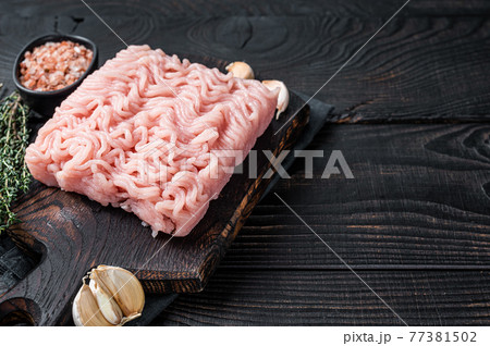Fresh Raw mince or ground chicken meat on wooden chopping board with thyme. Black wooden background. Top view. Copy space Fresh Raw mince or ground chicken meat on wooden chopping board with thyme. Black wooden background. Top view. Copy space 77381502