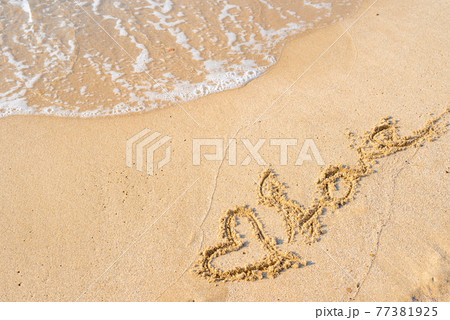 綺麗な海の浜辺の波打ち際に描かれたハートとlove 昼間 背景素材 の写真素材