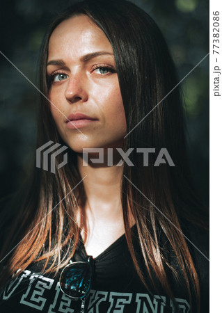 Portrait of a beautiful girl with gray eyes in a black t-shirt looking directly at the camera Portrait of a beautiful girl with gray eyes in a black t-shirt looking directly at the camera 77382086