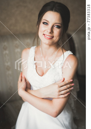 Beautiful bride wearing fashion wedding dress with feathers with luxury delight make-up and hairstyle, studio indoor photo shoot Beautiful bride wearing fashion wedding dress with feathers with luxury delight make-up and hairstyle, studio indoor photo shoot 77383318