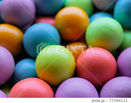 Background from multicolored bright small wooden balls of blue, yellow, red, lilac and green colors. A beautiful summer bright background for your projects. Background from multicolored bright small wooden balls of blue, yellow, red, lilac and green colors. A beautiful summer bright background for your projects. 77384121