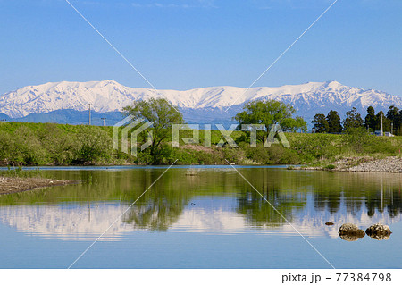 春の飯豊連峰と阿賀川（福島県・会津坂下町） 77384798