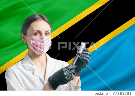 Girl doctor prepares vaccination against the background of the Tanzania flag. Vaccination concept Tanzania 77385281