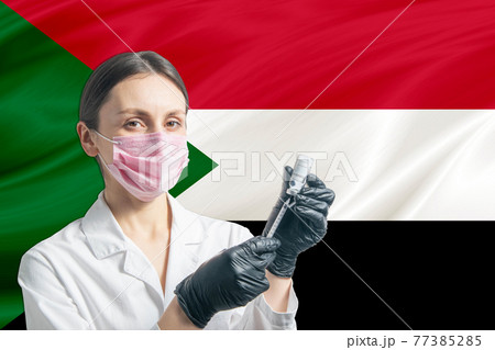 Girl doctor prepares vaccination against the background of the Sudan flag. Vaccination concept Sudan 77385285
