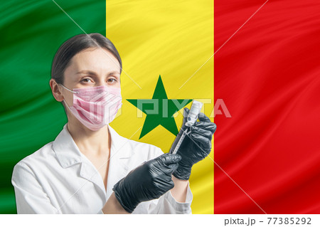 Girl doctor prepares vaccination against the background of the Senegal flag. Vaccination concept Senegal 77385292