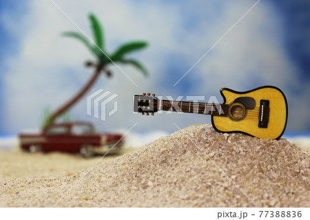 Guitar on Tropical Beach with Vintage Hot Rod in Background 77388836